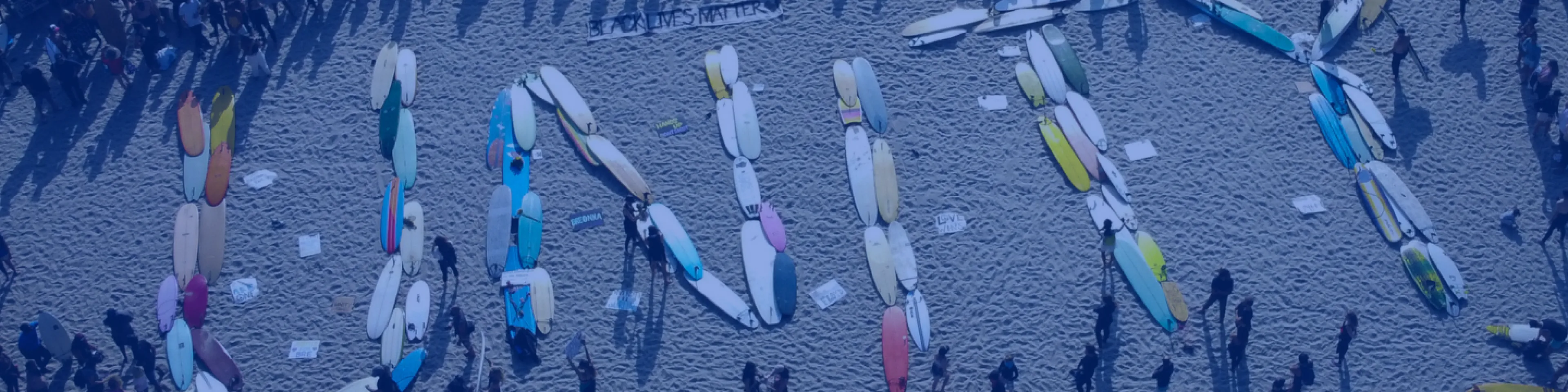 Una serie di tavole da surf sulla spiaggia disposte a formare la parola "Unità".