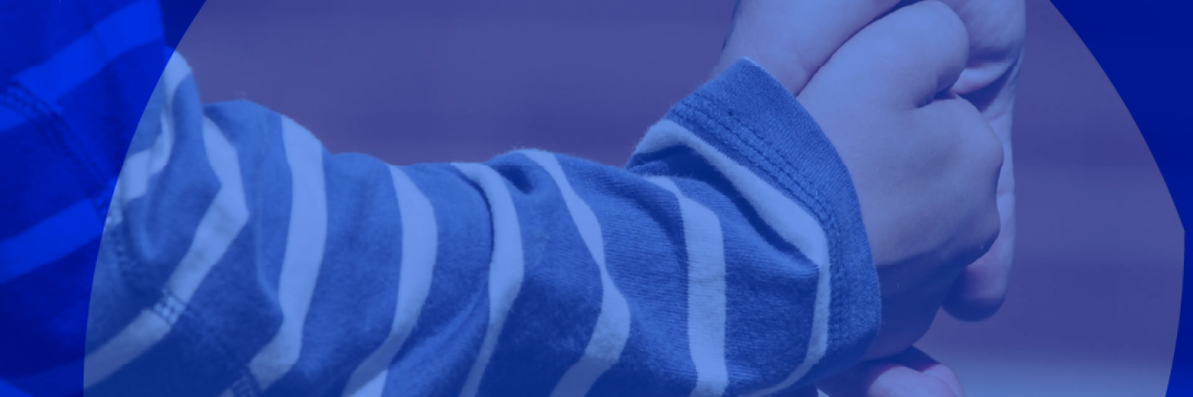 Particolare della mano di un bambino nella mano di un adulto.