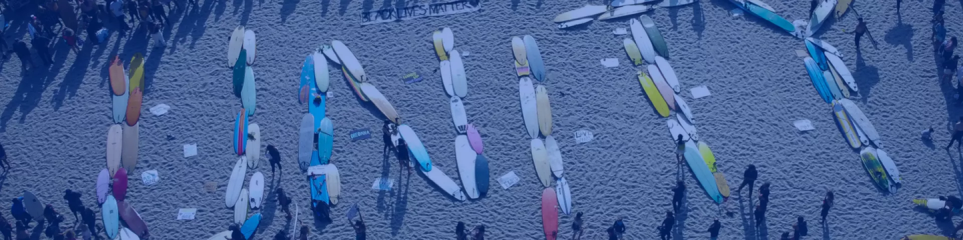 Seria desek surfingowych na plaży ułożonych w słowo „Unity” (Jedność).